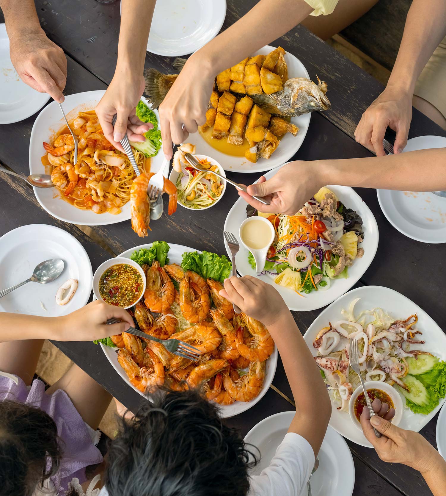 Aerial of hands reaching around a table of seafood